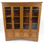 Oak bookcase with Greek key cornice above two pairs of glazed doors, each enclosing three adjustable