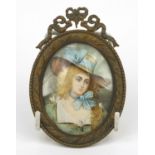 Portrait miniature of a girl wearing a bonnet, housed in a brass swag design frame, 10cm high