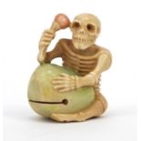 Oriental netsuke of a skeleton playing a drum, signature to the base, 5cm tall