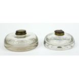 Two large Edwardian glass inkwells with hinged brass lids, the larger 13cm diameter