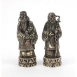 Two oriental Chinese silver figures, both of elders - one holding a child, both wearing gowns and