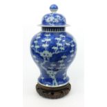 Large oriental Chinese ginger jar and cover hand painted with prunus decoration, on a carved