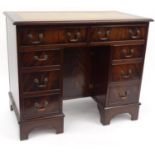 Mahogany kneehole desk with tooled leather insert top and fitted with eight drawers, 76cm high x