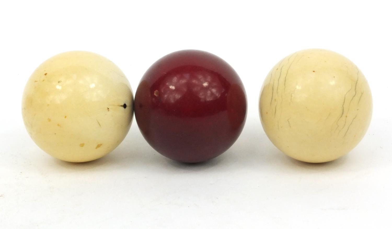 Three ivory snooker balls, the largest 4.5cm diameter