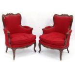 Pair of French carved walnut armchairs with red upholstery and floral carvings