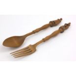 Wooden spoon and fork carved with Continental style figures, each 29cm long Generally good