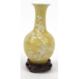 Oriental Chinese porcelain vase decorated with a white prunus pattern, mounted on a carved wooden