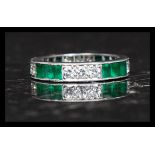 An 18ct platinum, diamond and emerald eternity ring.