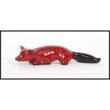 A Royal Doulton Flambe figure of a crouching fox, bold black and red colouring,