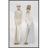 A pair of tall  Nao ceramic figures of a lady and a gentleman playing croquet being signed to the