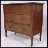 An early 20th century oak straight three chest of drawers, raised on stub legs.