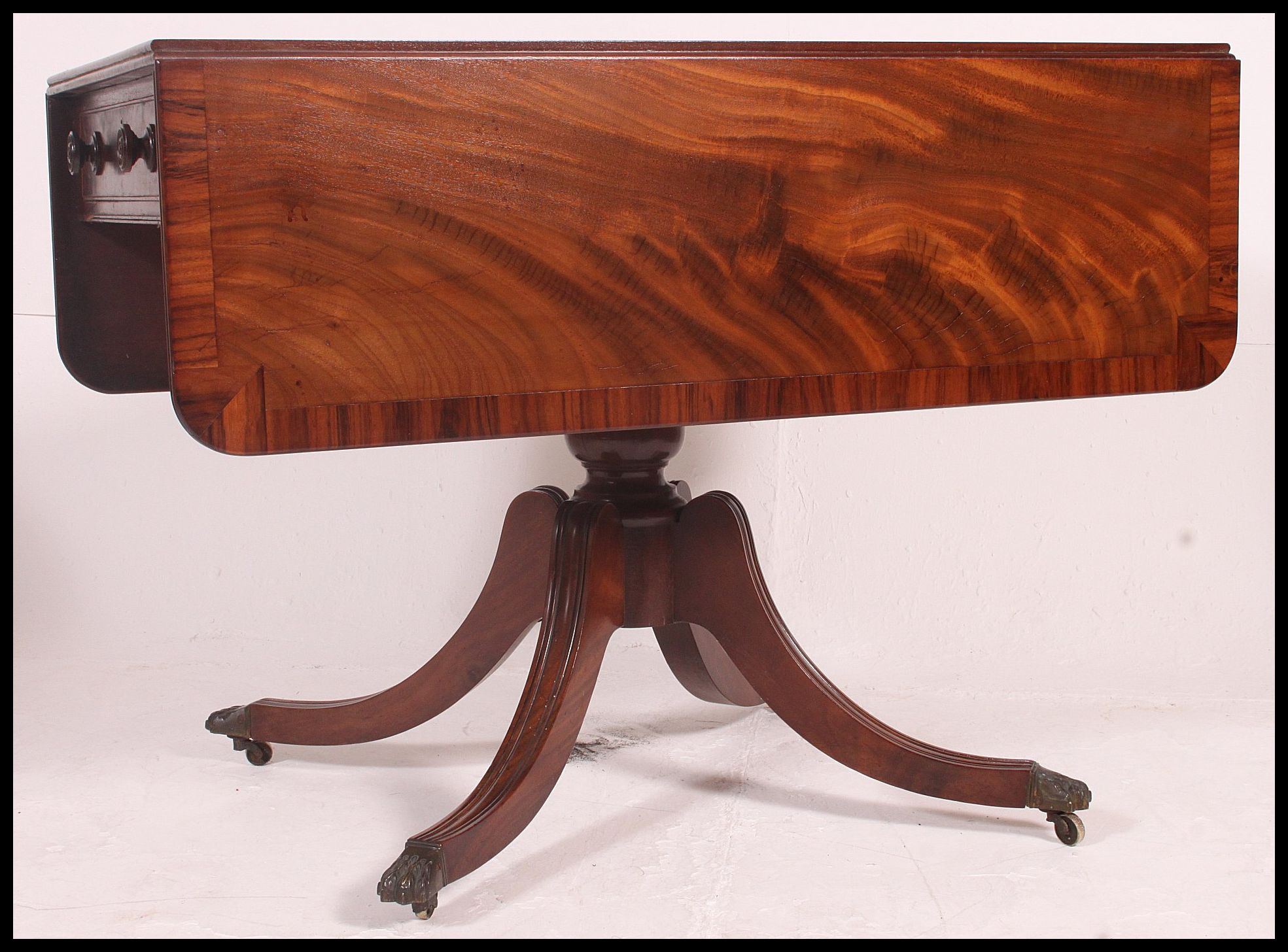 A Regency 19th century flame mahogany sofa table being raised over a good quadruped base with drop