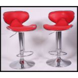 A pair of retro style red faux leather and chrome gas pump adjustable bar stools,