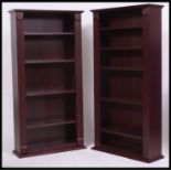 A pair of faux rosewood veneer upright open window bookcase cabinets.