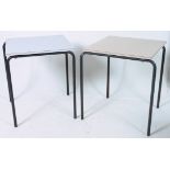 A pair of retro industrial school tables having a melamine top raised above metal tubular legs.