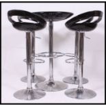 A contemporary set of four rise and fall hydraulic pump action chairs along with a matching table