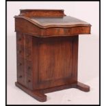 A Victorian walnut Davenport desk with hinged top having sectional interior.