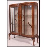 A 1930's walnut Queen Anne revival china display cabinet being raised on cabriole legs with glass