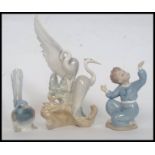 A Lladro figurine of a finch together with a Lladro small boy and a Nao figurine of storks.