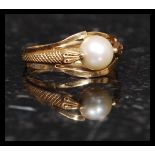 A 18ct gold and pearl ring having a snake adorned split shank,