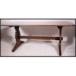 A large Golden Dawn Ercol refectory dining table raised on lyre shaped supports.