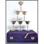 A case of six silver metal wine goblets having a  hand beaten effect presented in a blue velvet