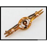 A 9ct twin bar brooch with central floral motif and applied finials. Marked 9ct. Weight 1.