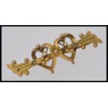 A 9ct gold early 20th century sweetheart brooch having intertwined hearts with filigree worked bar,