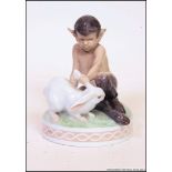 A Royal Copenhagen porcelain figure group of a young faun playing with a white rabbit.