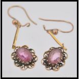 A pair of 9ct gold drop earrings having a central cut polished pink glass stone