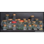 A collection of kitchen glass jars of various sizes and shapes, some with cork stoppers.