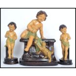 A 1930's plaster fairground prize of young child / cherub sat on a plinth with a playful kitten