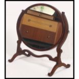 An Edwardian oval mahogany toilet swing mirror together with a mahogany fire screen with shelf to