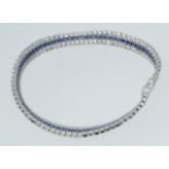 A contemporary  silver cz stone and sapphire set tennis bracelet, each stone being claw mounted.