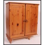 A contemporary pine side cabinet. Twin full length doors with shelved interior and flared top above.