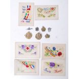 A group of seven WWI silk postcards along with a pair of brass RAF cap badges,