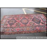 A large Turkish / Persian handwoven rug having red ground with blue spandrels and geometric black