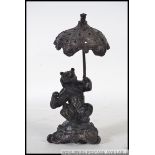 A bronze hollow cast bronze bear with umbrella raised on a naturalistic plinth base