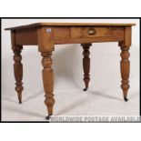 A Victorian pine kitchen dining table raised on turned reeded legs with fitted frieze having single