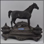 A cast bronze inkwell in the form of a horse on an ornate base with hinged inkwells,