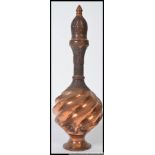 An Indian copper decorative twist design shaped bottle.