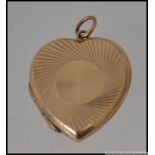 A 9ct gold locket pendant in the form of a heart with geometric etched decoration.