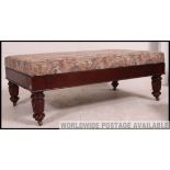 A large mahogany upholstered foot stool / pouffe raised on regency mahogany legs with castors