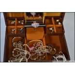 A large silk lined musical jewellery box containing a good selection of costume jewellery to