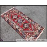 A large early 20th century handwoven rug / runner of having red ground with geometric borders and