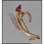 A 9ct gold brooch in the form of a tulip with diamond pave set leaves and a central ruby flower