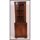 A 20th century mahogany corner display unit with three adjustable shelves to the upper section and