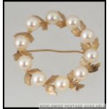 A 14ct gold and pearl ladies brooch of circular form, the pearls intertwined with leaves.