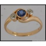 An 18ct gold ring with central blue stone flanked by two 5pt diamonds in bezel settings Marked 18ct