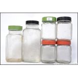 A collection of vintage / retro glass storage jars with different colour screw twist lids